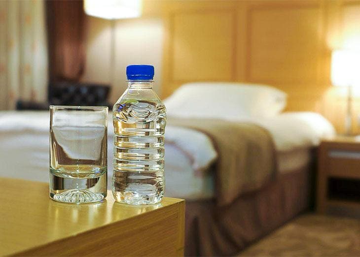 A glass and a bottle on the table of the hotel room 